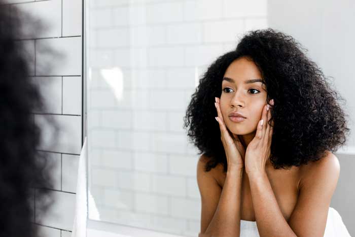 woman looking at clear skin in mirror