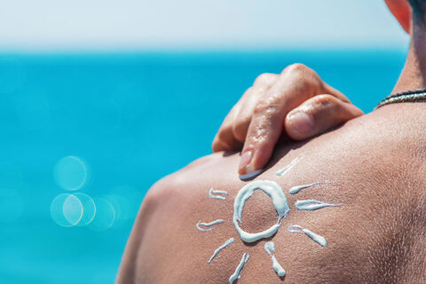 A man applying sunscreen on his back.