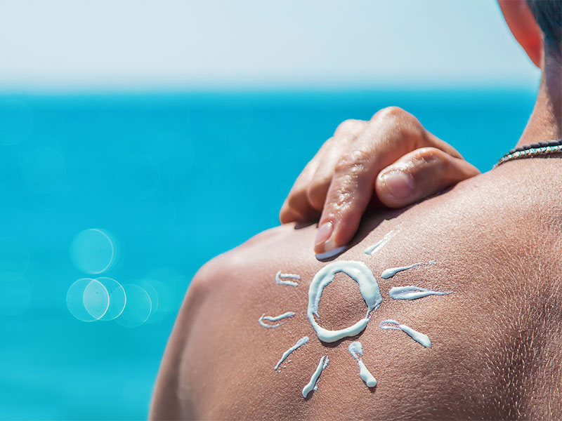 A man applying sunscreen on his back.